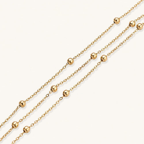 Three-strand gold-plated bracelet with clustered ball beads and adjustable clasp on cream background